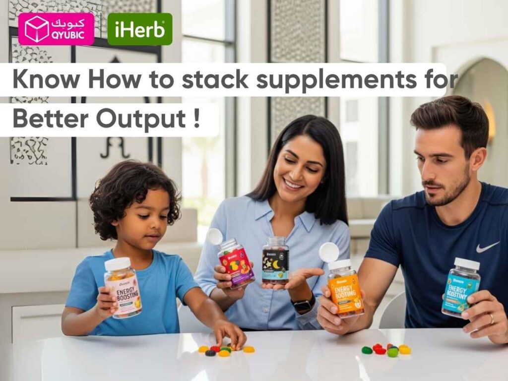 A family, including a young child, a woman, and a man, happily looking at various gummy supplements on a white table. The child holds a bottle labeled "Energy Boosting," while the woman holds bottles with moon and star designs, and the man holds a blue bottle. Colorful gummy vitamins are scattered on the table. The image also displays the text "Know How to stack supplements for Better Output!" and features the QYUBIC and iHerb logos.
