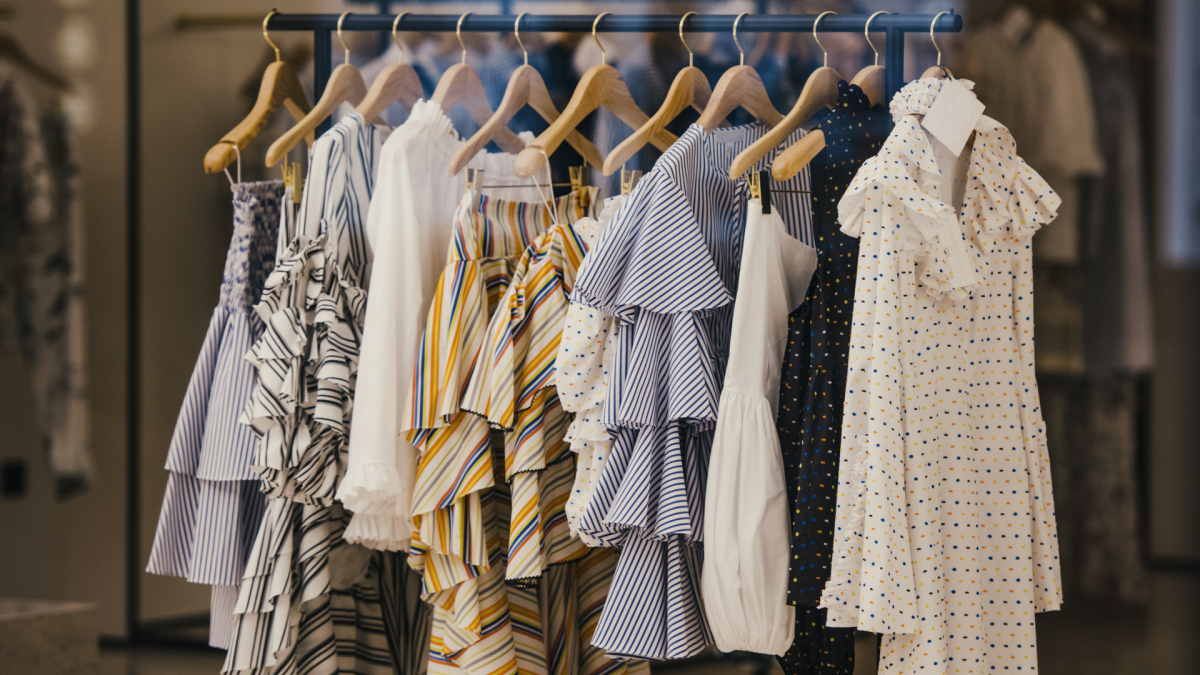 A retail store with colorful clothing items hanging on black racks, including t-shirts, dresses, and casual wear. A Levi’s t-shirt is prominently displayed.