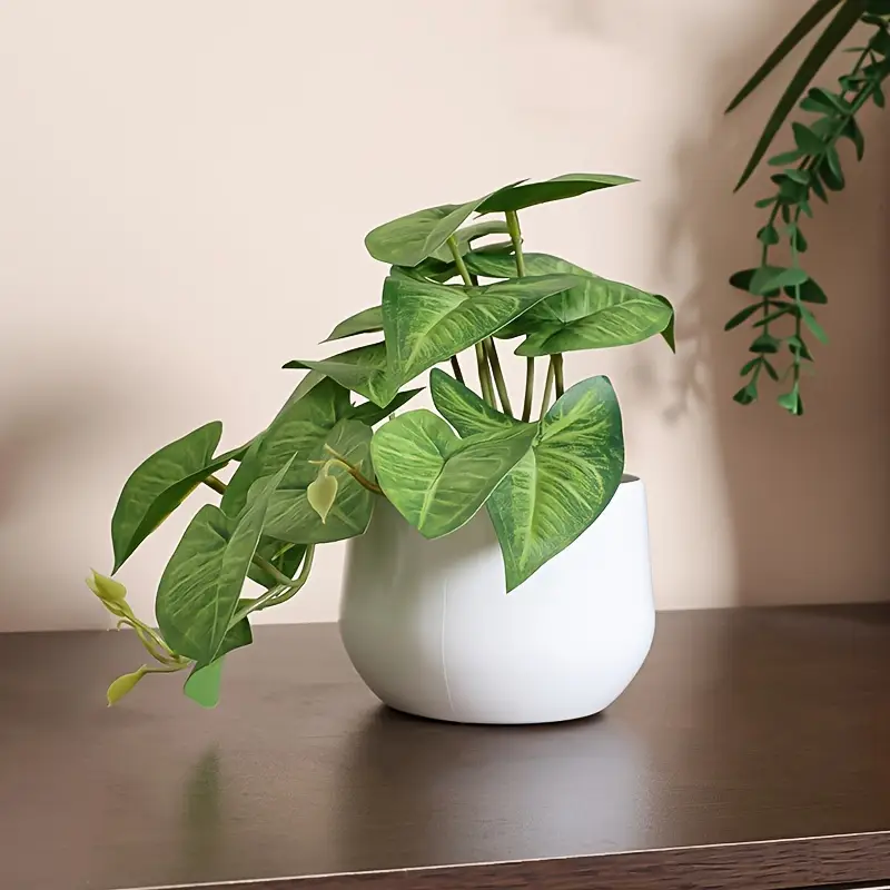 Artificial green plant with heart-shaped leaves in a white pot, placed on a wooden surface.  A great stress relief gift idea.